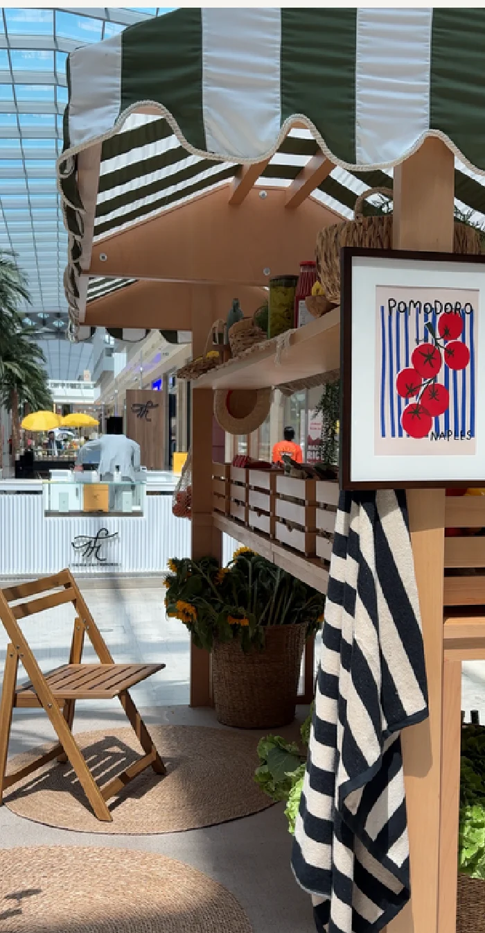 Italian market-style booth with striped awning, produce crates, and vintage signage