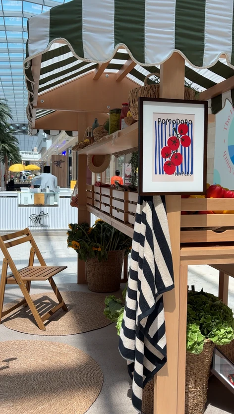 Crates of fresh produce and sunflowers styled beneath the striped market awning